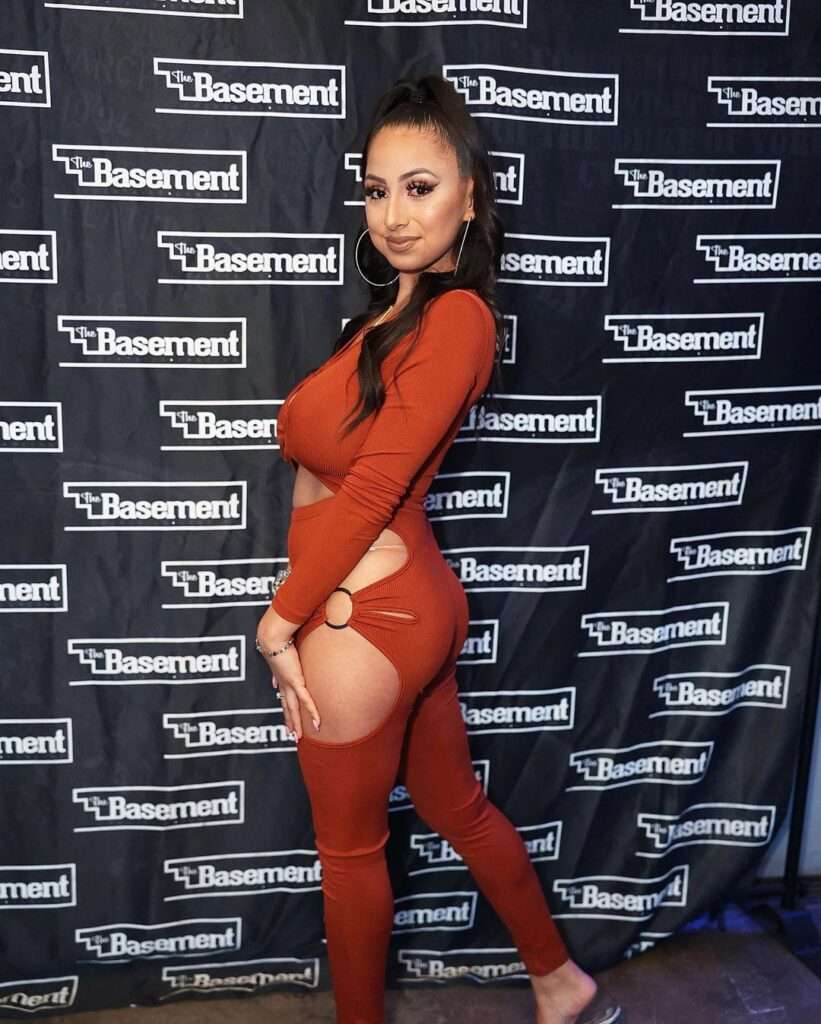 Ginger in the sexy jumpsuit pair with large hoops while poses for a photo