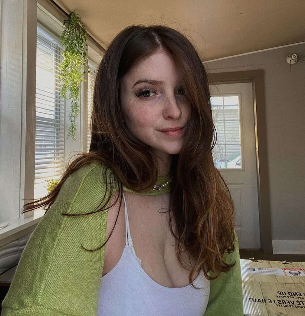 Paige Mousseau in the white tank top pair with green top while taking a selfie