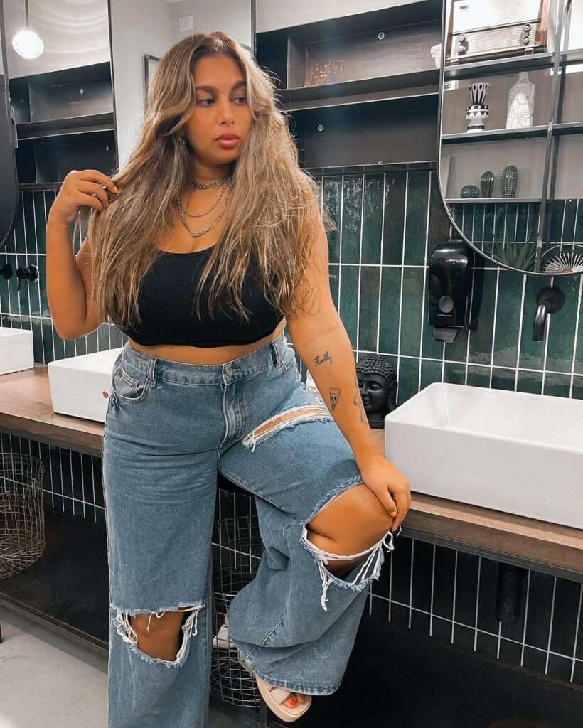 Shahar Matok in the black crop top pair with blue baggy jeans while poses for a picture