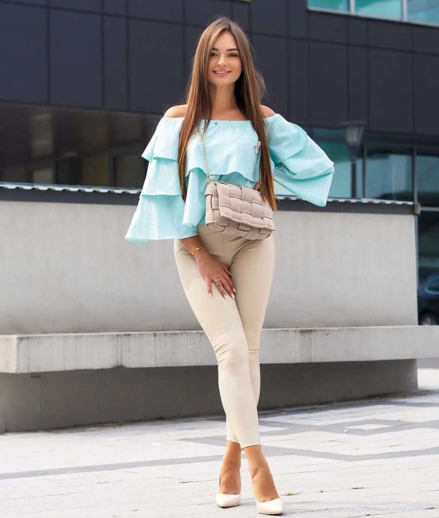 Sylwiaaa wearing a birght sky blue top pair with brown pants and smiling towards camera