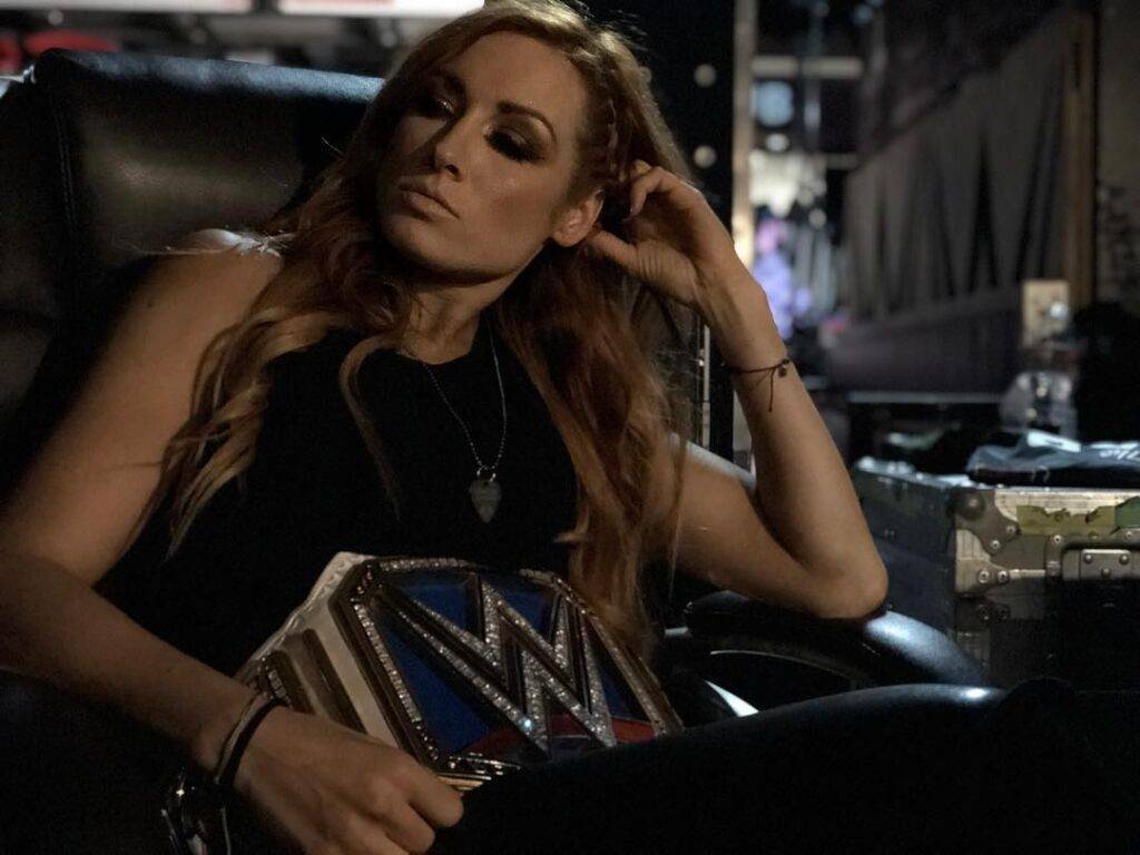 Becky Lynch wearing the WWE belt and sitting and posing for the picture