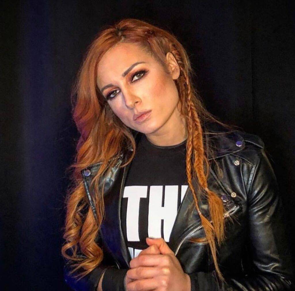 Becky Lynch wearing black shirt over black jacket and posing for the picture