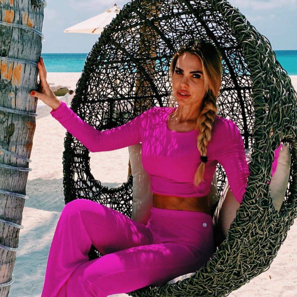 Ilary Blasi wearing pink trouser and shirt or sitting behind ocean and posing for the picture