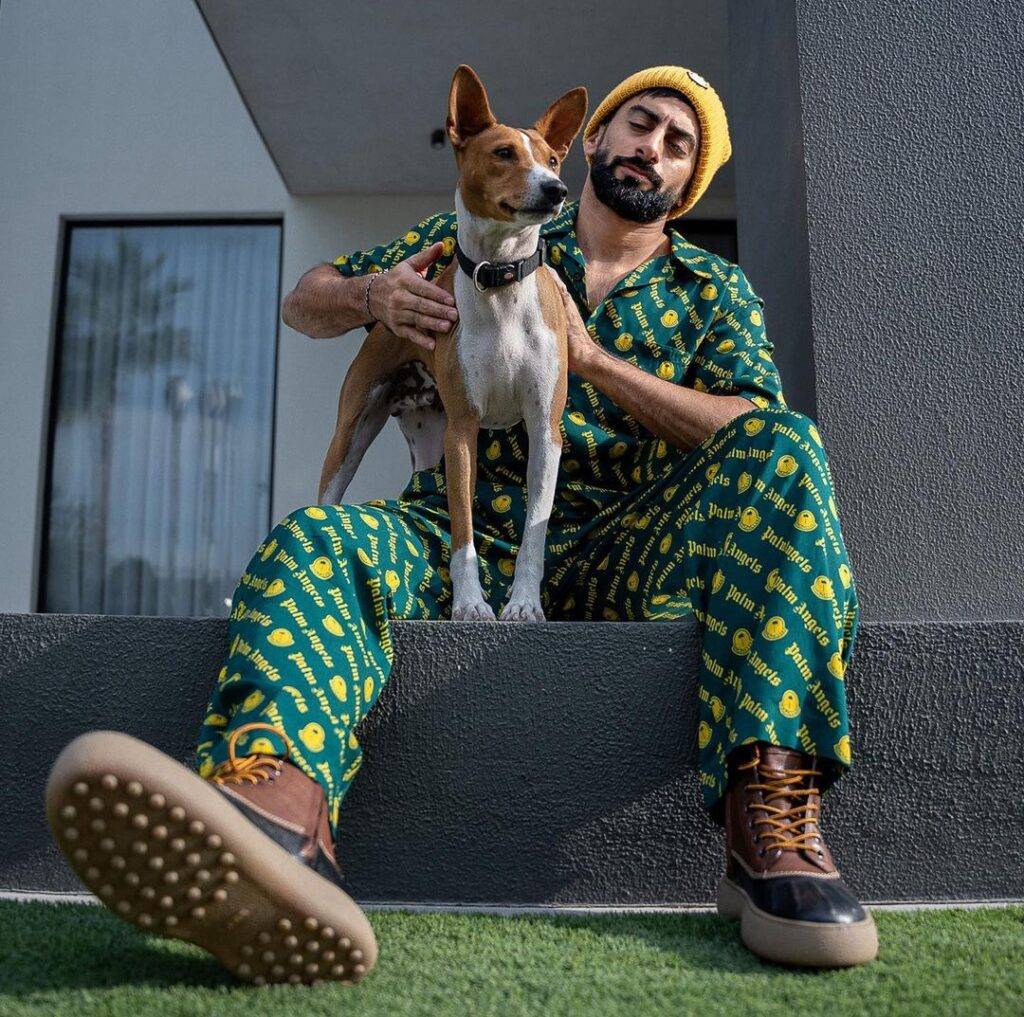 Anas Bukhash in the green printed pair with yellow cap and black sneakers while looking at his dog