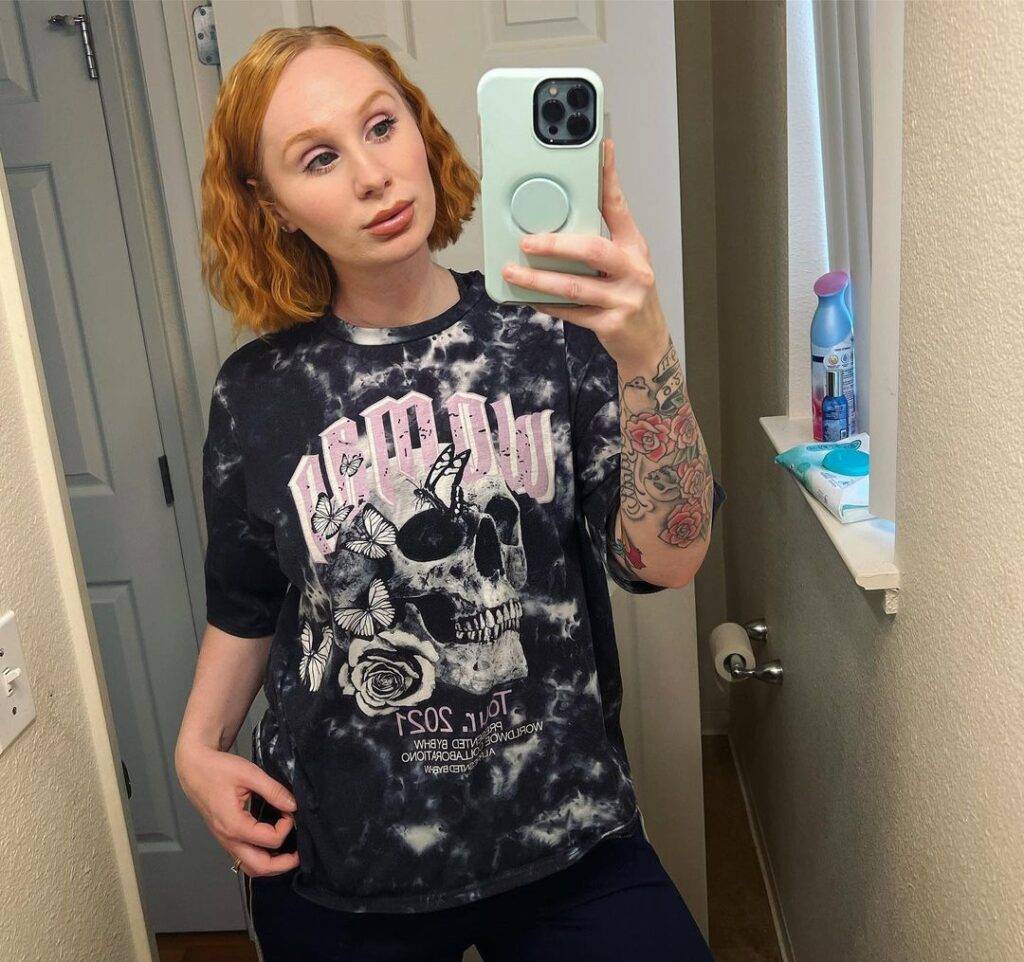 Ashley Elliott in the printed tie and die shirt pair with black shorts while taking picture in the front of mirror