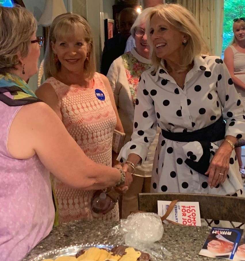Jill Biden is laughing and is smiling while shaking hand with other lady and is posing fora picture.