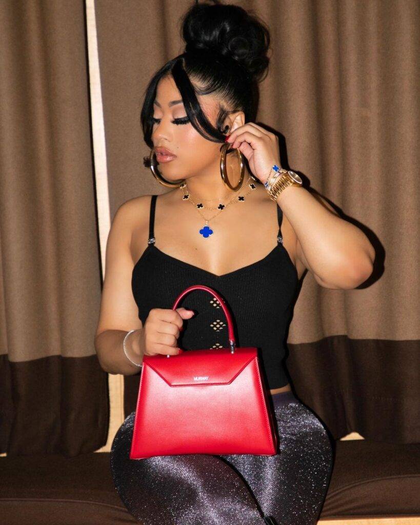  Hennessy Carolina in the black sexy dress pair with red bag and poses for a photo