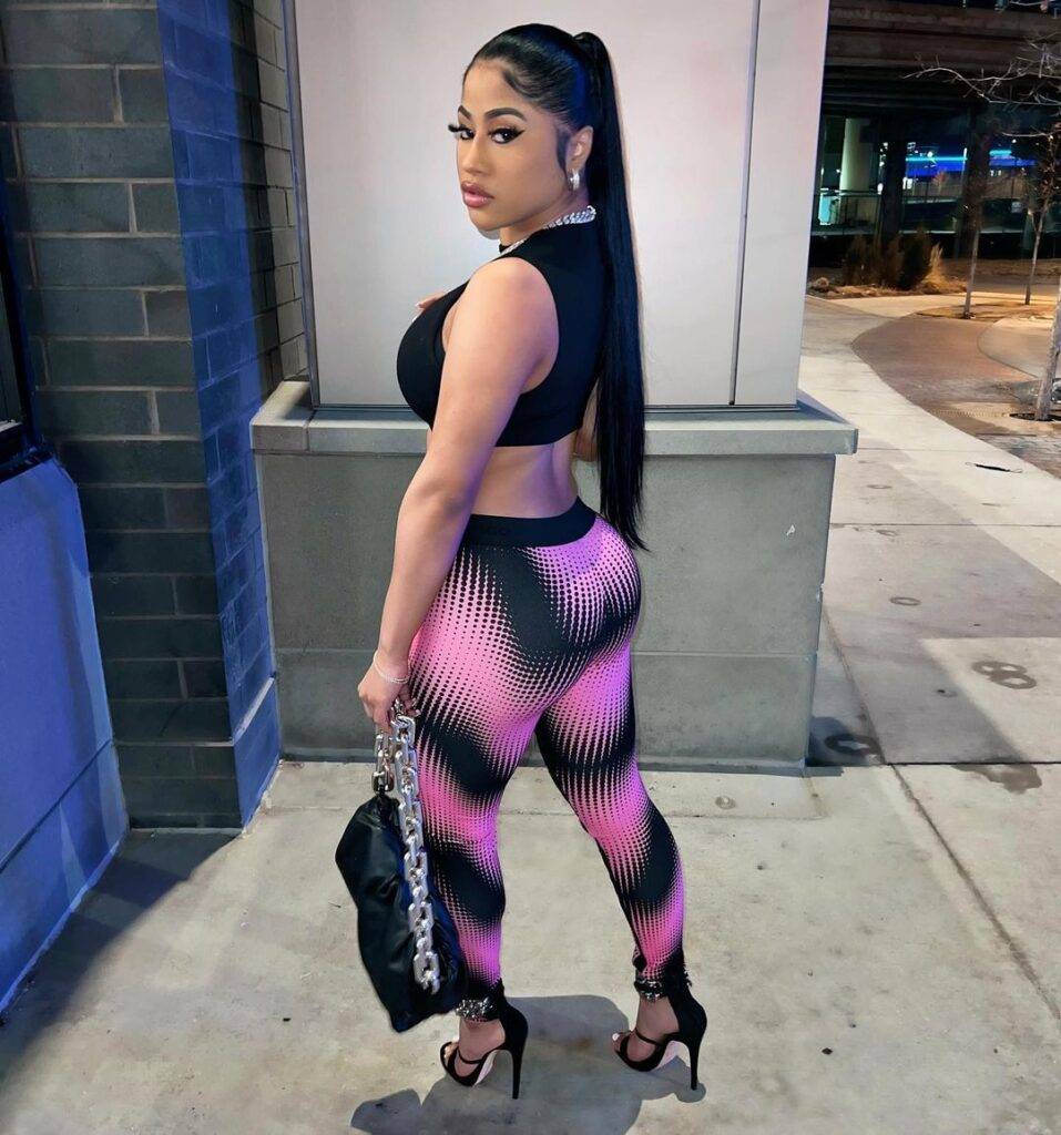 Hennessy Carolina in the black crop top pair with printed leggings and bag while showing side back pose towards camera