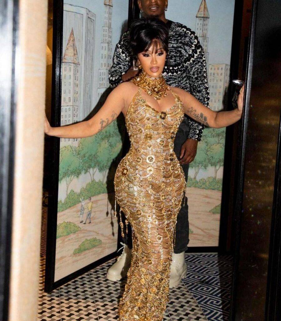 Cardi b in the golden fancy dress pair with heavy jewellery while looking towards camera