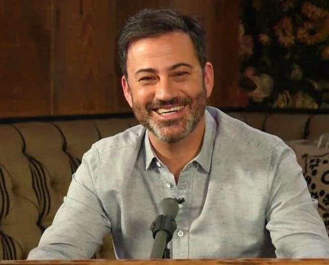 Jimmy Kimmel is laughing while posing for a picture while doing hosting.