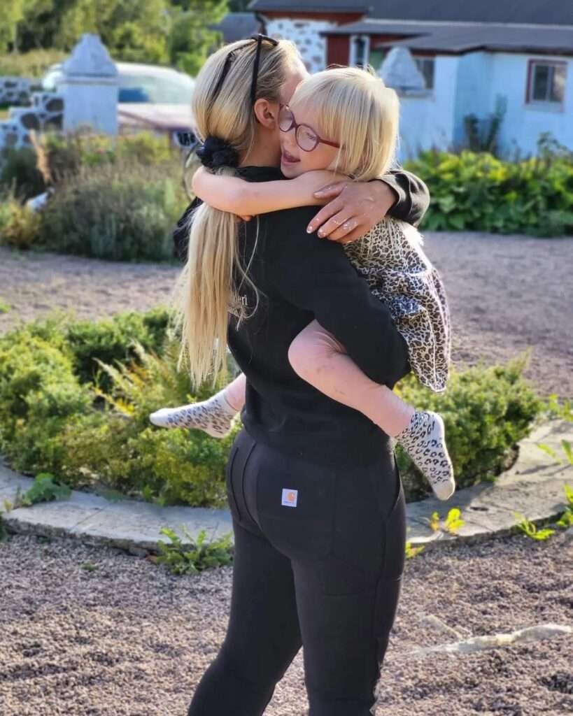 Johannna juhlin in the black sexy outfit while holding her daughter in the outdoors