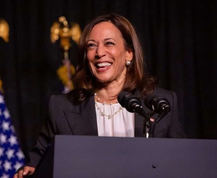 Kamala Harris is laughing and is addressing to her nation while wearing a business suit.
