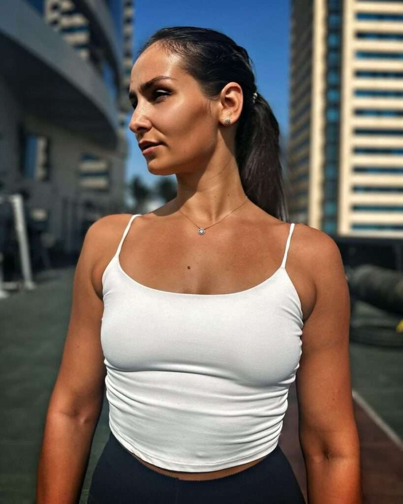 Katarina Kavaleva is posing for a picture while wearing a sleeve less shirt and pant.