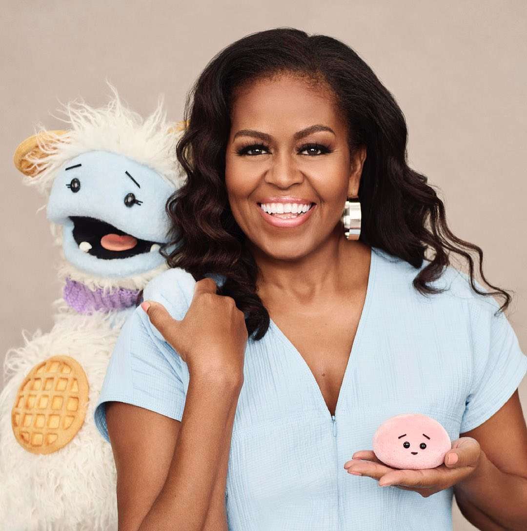 Michelle Obama is smiling while posing on the picture and is wearing the stylish shirt.