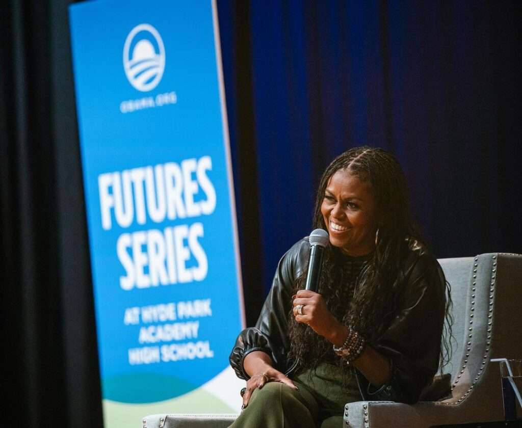 Michelle Obama is talking and smiling in a show and is talking about the future series and national issues.