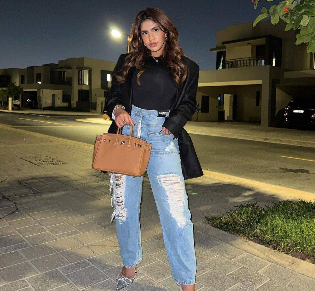 Noor Stars in the black shirt pair with blue jeans matching coat, heels, and brown bag
