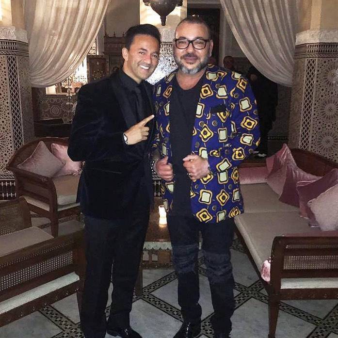 RedOne is wearing the full black outfit pair with black velvet coat and shoes while taking a picture with making of morocco