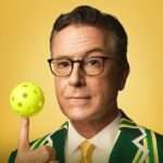 Stephen Colbert is promoting his show and spinning ball on his hand to show himself funny.