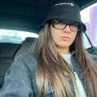 Alice Ardelean is wearing the white shirt, jacket, glasses and cap or taking selfie