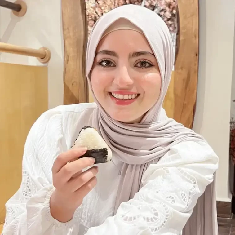 Amina DEHBI taking a picture while she is smiling and eating sushi