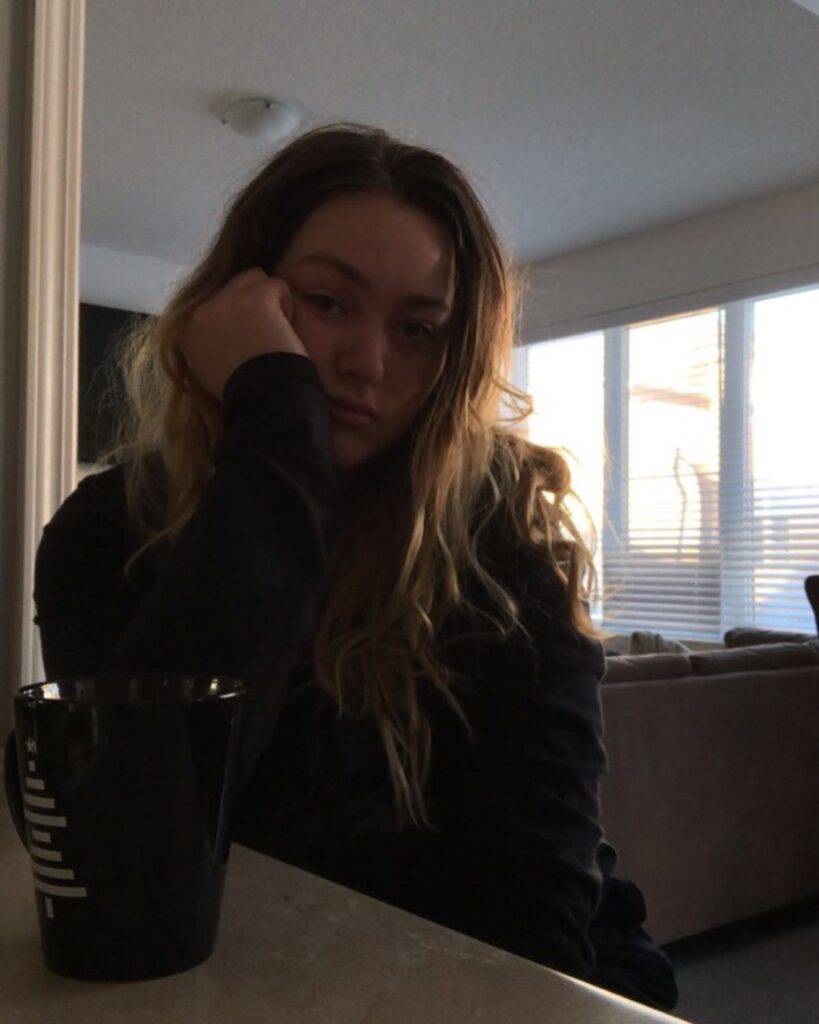 Brookiebaby is wearing black clothes and sitting in front of a black cup or posing while taking the picture