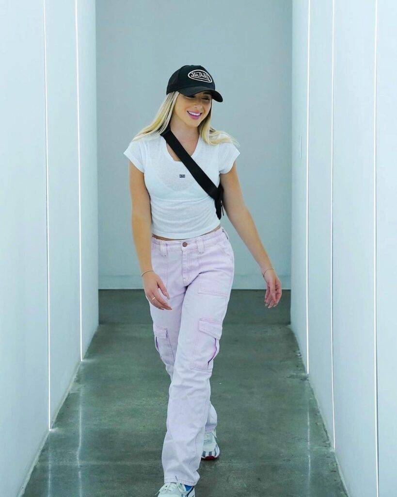 Jessica Macrina is wearing white t shirt, pant and hat or smiling while posing for the pictrue