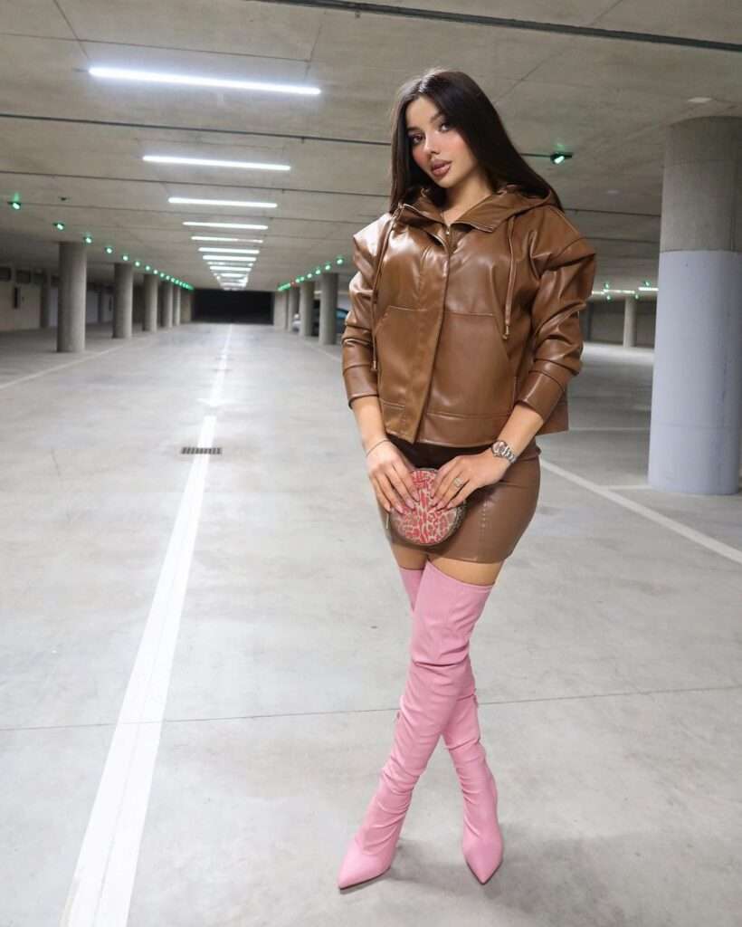 Rashel Kolneci is wearing brown jacket and skirt or pink long shoes or posing while taking the picture
