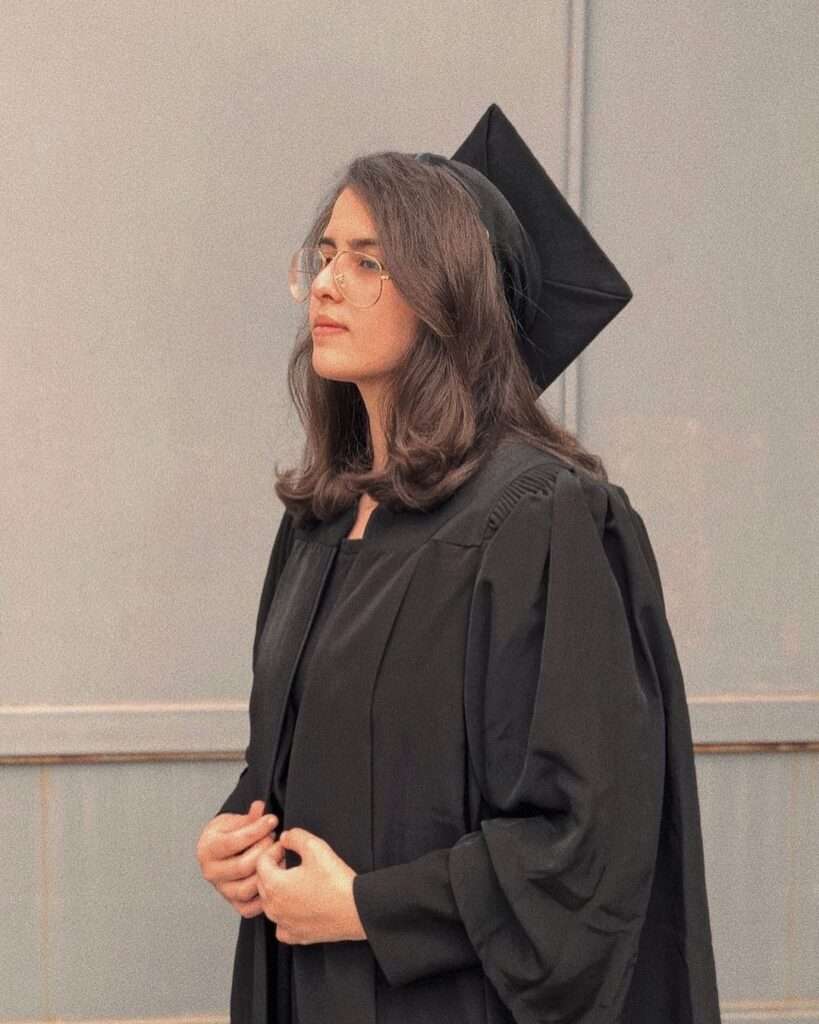 Toomacooks is wearing the graduation cap and black coat or posing while taking the picture