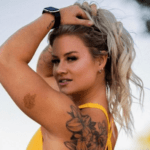 Dani Elle Speegle in the yellow stripped top pair with earrings and smart watch while poses for a photo