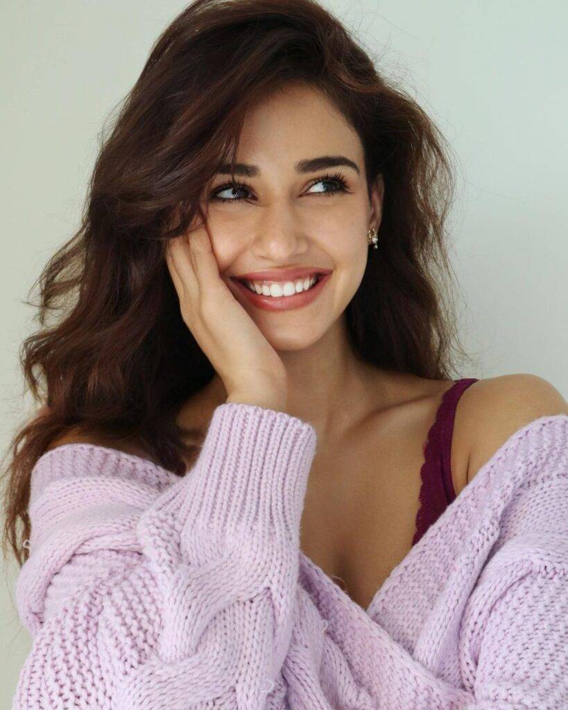 Disha Patani in the pink bra pair with purple sweater while smiling and poses for a photo