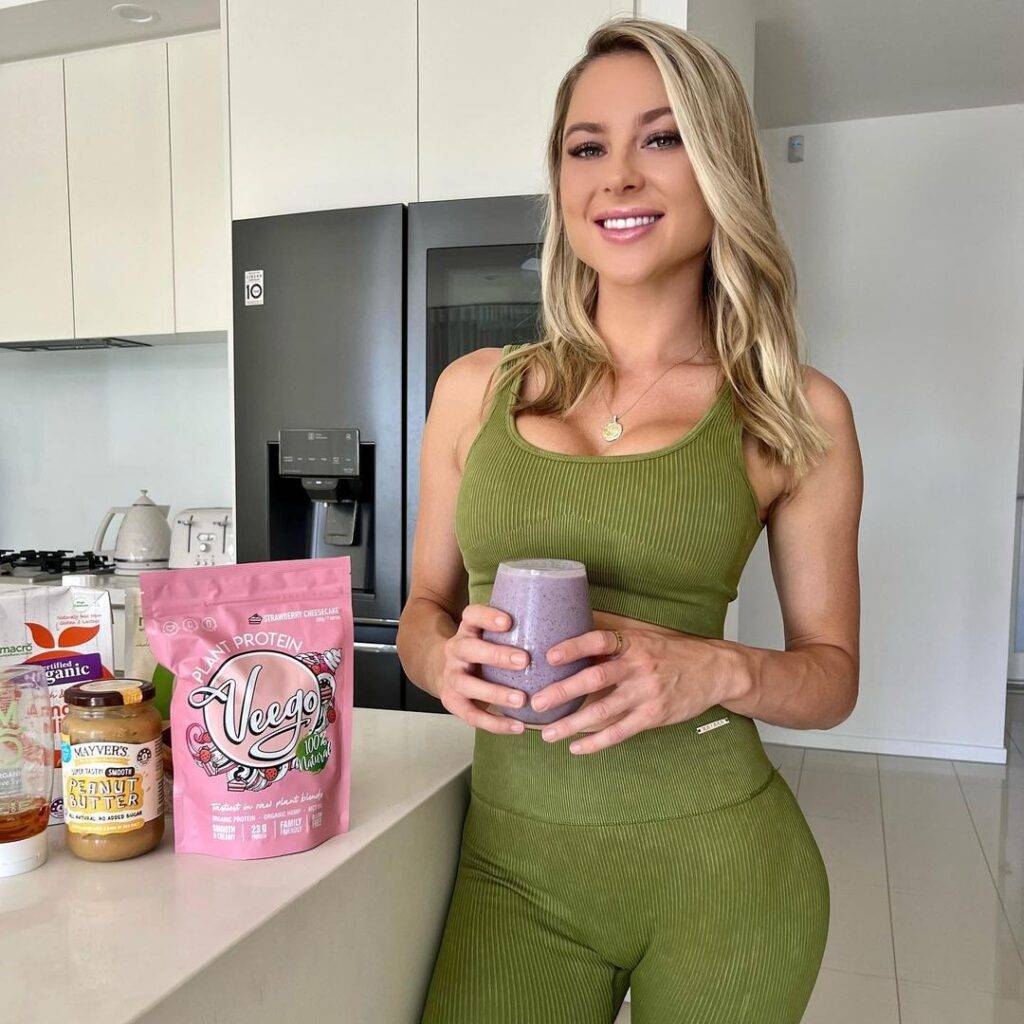 ilana collins in the green 2-piece legging set while holding a smoothie glass in her hands and smiling towards camera