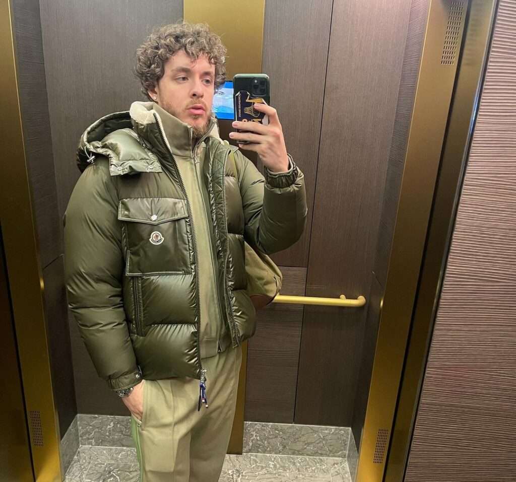 Jack Harlow in the green dress pair with a green water proof jacket while taking picture in the front of mirror