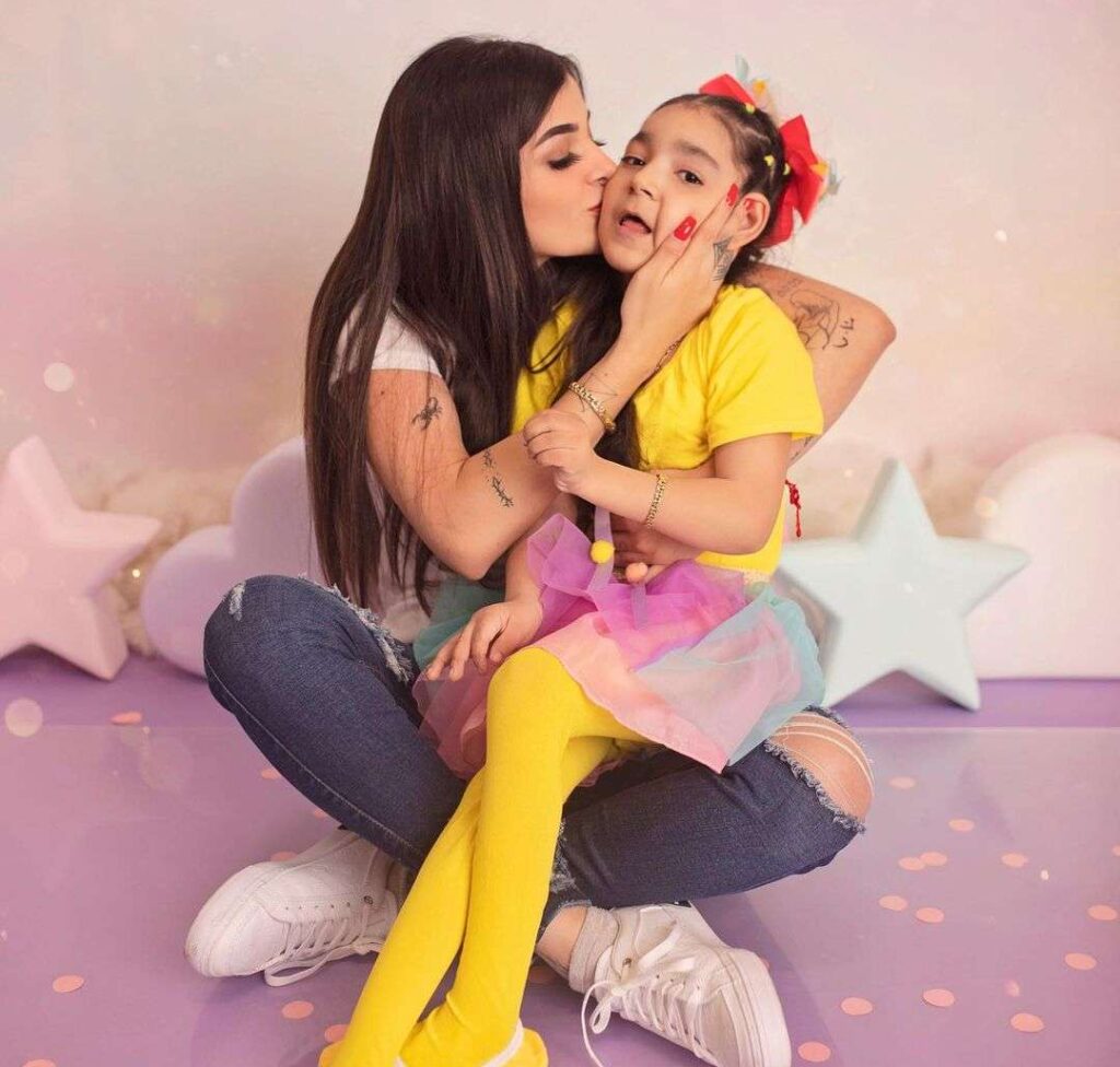 Karely Ruiz in the white t-shirt while kissing her daughter while taking a photo