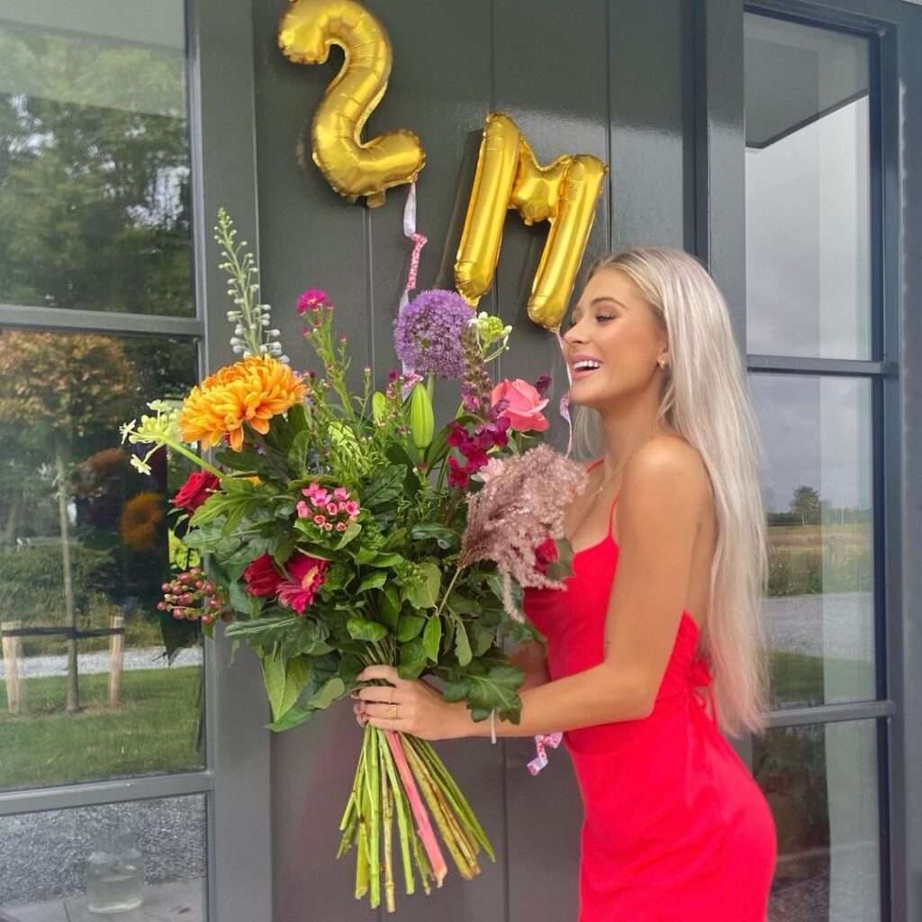 Quinty in the red striped bodycon while holding a flower bouquet in her hands