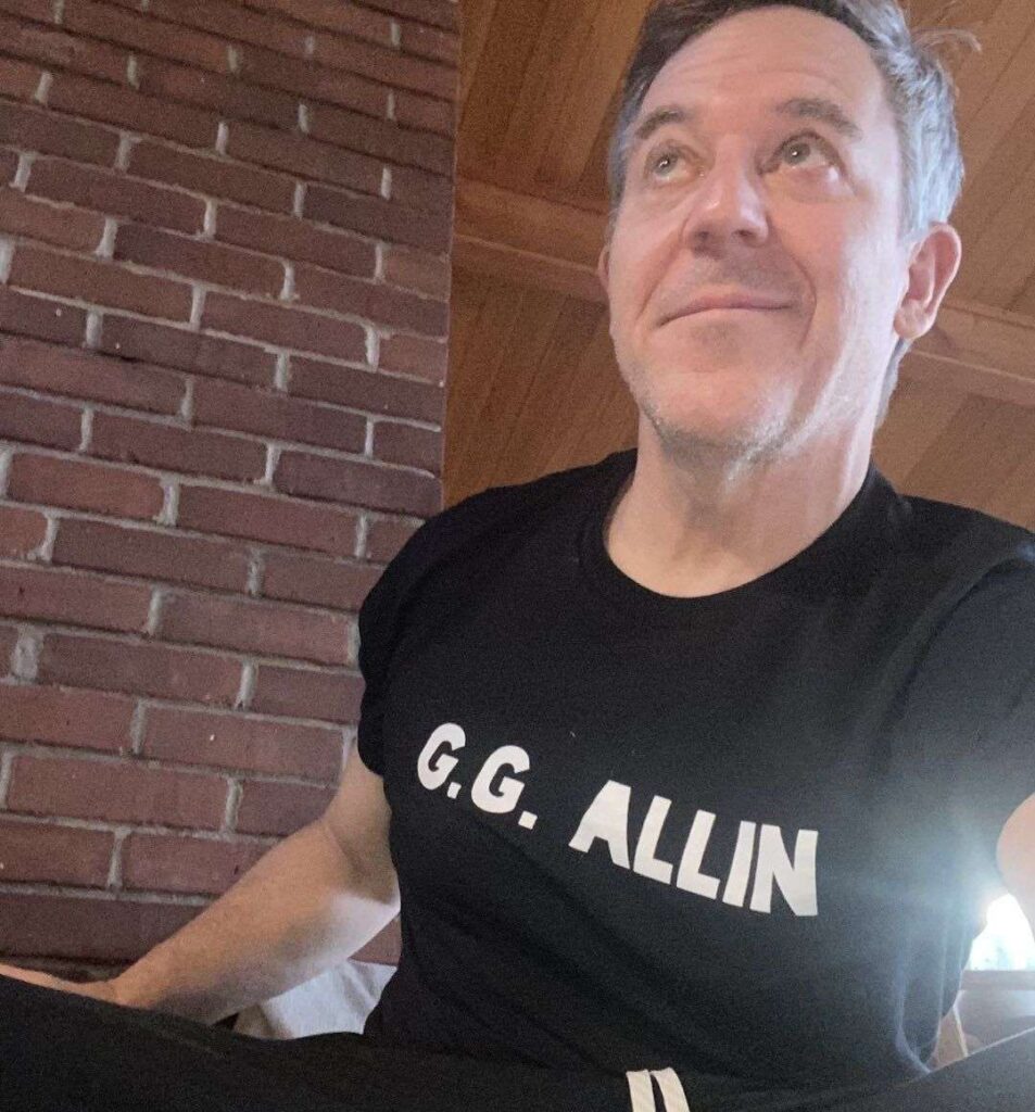 Greg Gutfeld in the black t-shirt and trouser while taking a down selfie
