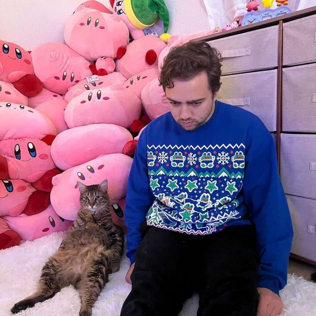 Mizkif in the blue sweatshirt pair with black trouser while taking picture with a cat