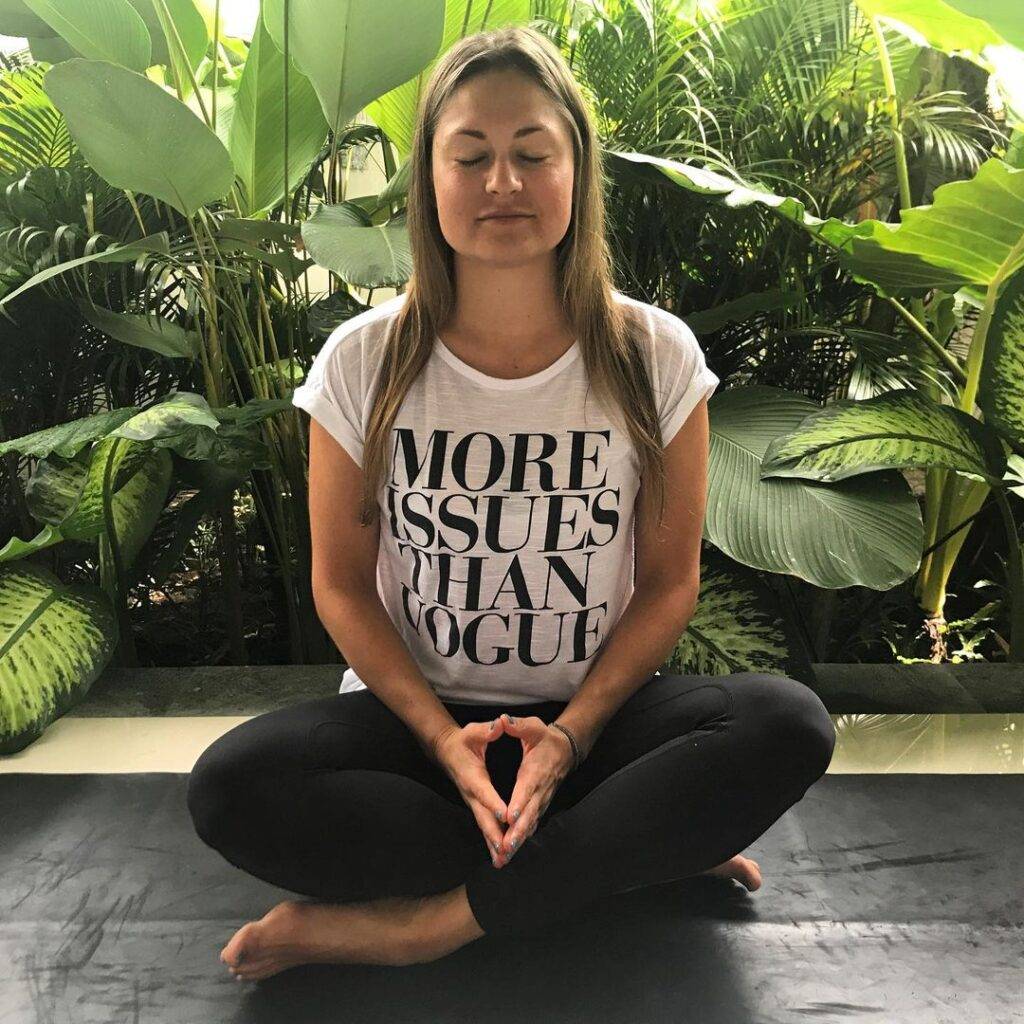 Amanda E. in the white printed t-shirt pair with black leggings while sitting for yoga
