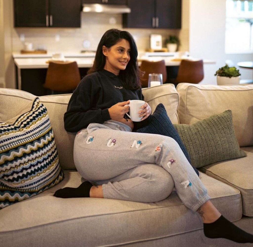 Toor Manpreet in the black crop top pair with grey leggings while holding a cup of coffee and poses for a photo