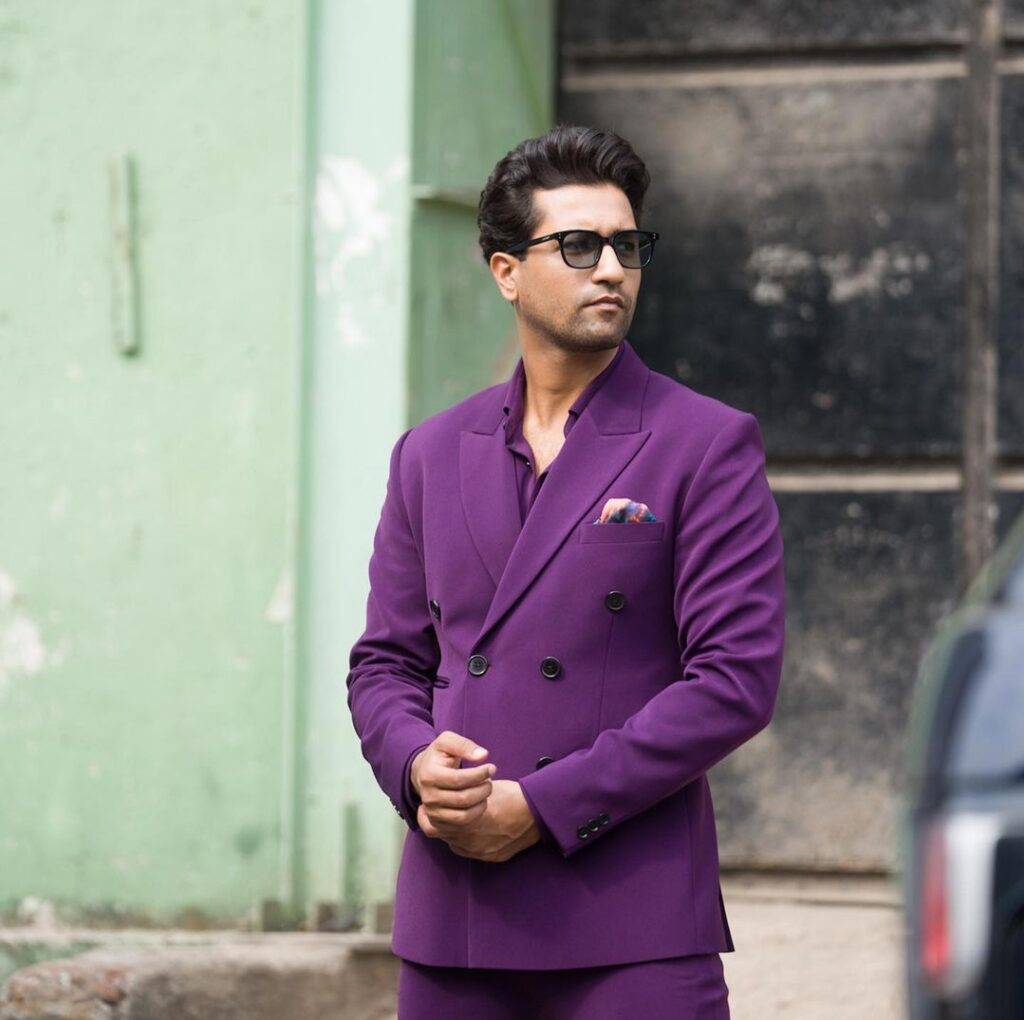 Vicky Kaushal in the dark purple 3-piece suit pair with black shades while poses for a photo