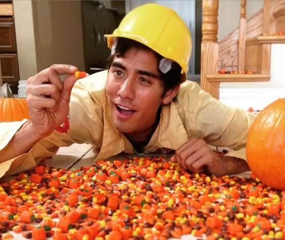 Zach king in the yellow dress shirt pair with yellow cap while taking picture with a pumpkin