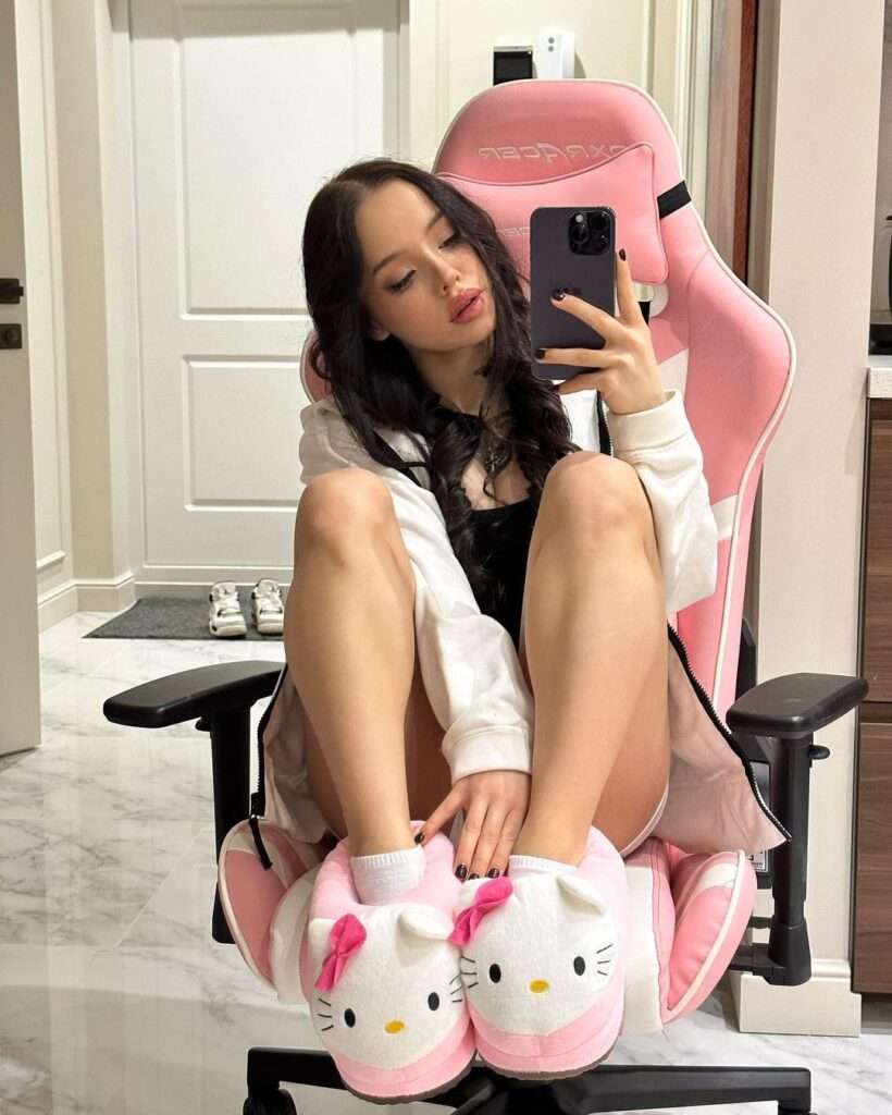 Lyna Com 2000 is wearing white shirt and sitting on pink chair while posing for the picture