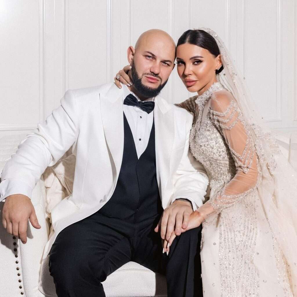 Oxana Samoylova is wearing her wedding dress and posing for the picture with his husband