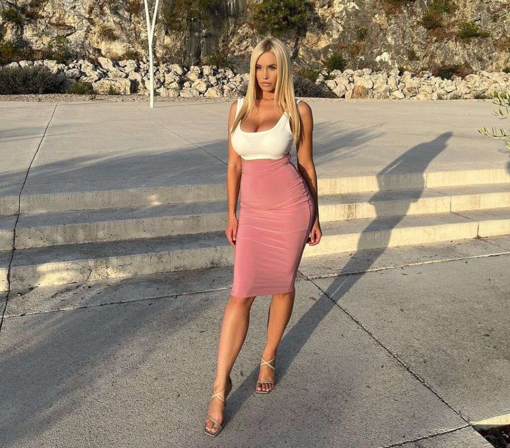 Andelalede in the white tank top pair with pink skirt pair with strapped heels while poses for a photo
