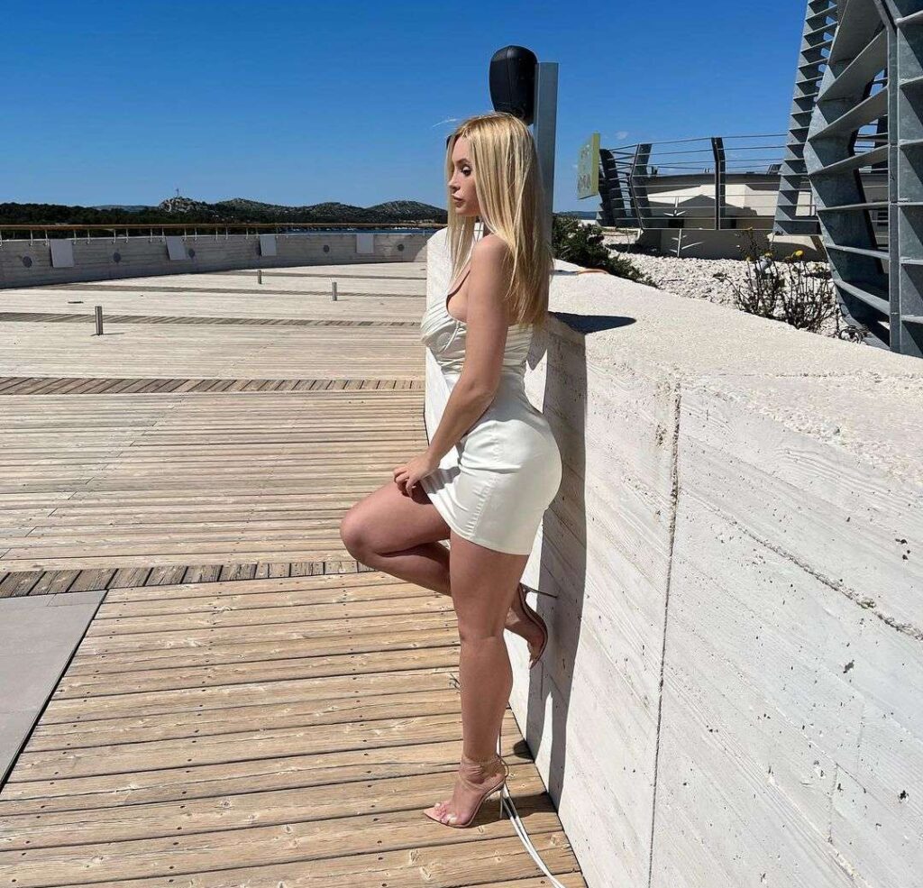 Andelalede is looking sexy in the white mini dress pair with matching heels while poses for a photo