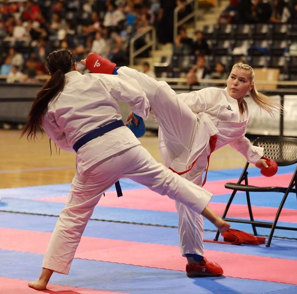 Kiana Daigneault is while playing Karate as she is fighting with a girl while wearing a Karate suit.