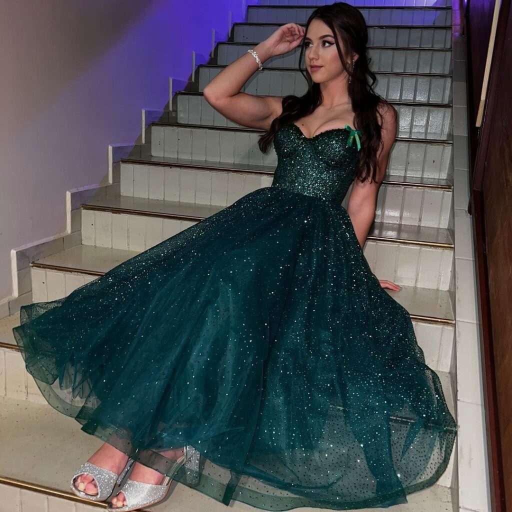 Lucia Mikusova is sitting on stairs while wearing a long maxi while keeping her right hand on her face.