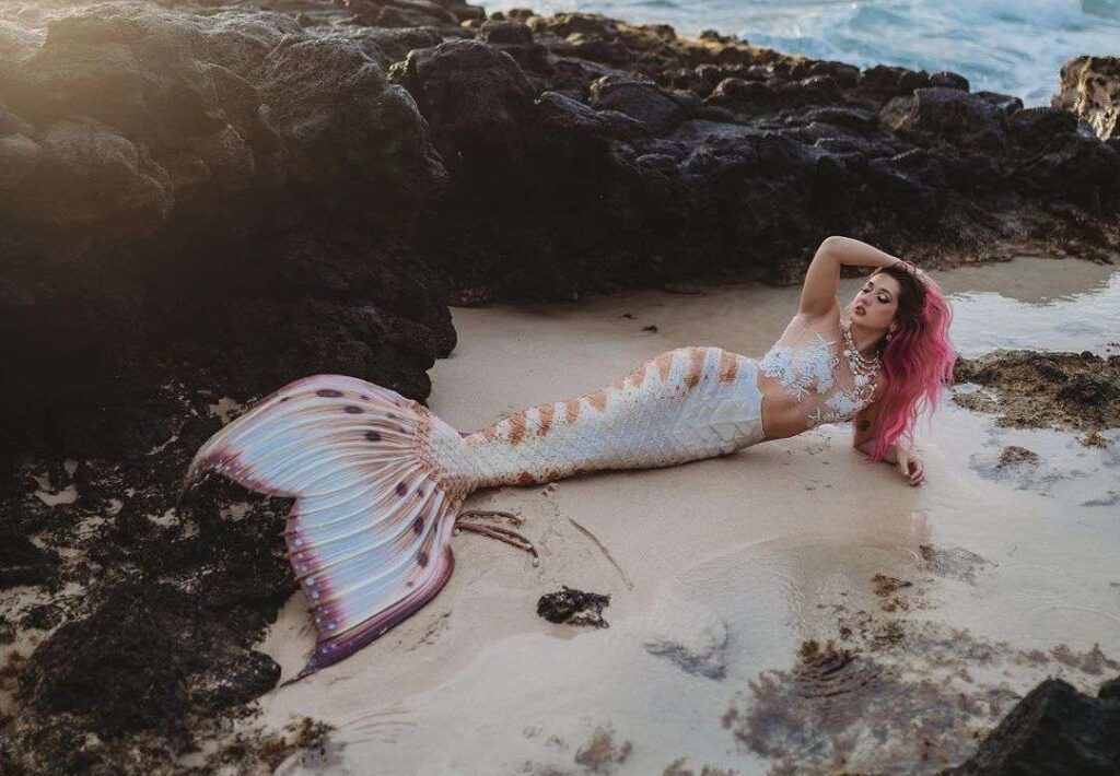 Mermaid Sirenity is looking hot in the white and brown fish like costume while laying on the sea shore