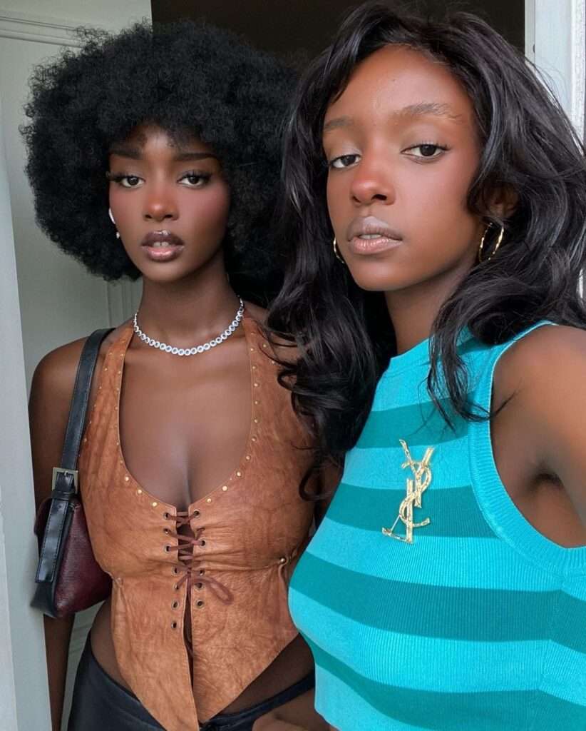 Queenblackpanther is posing for a picture as she is standing with her younger sister.