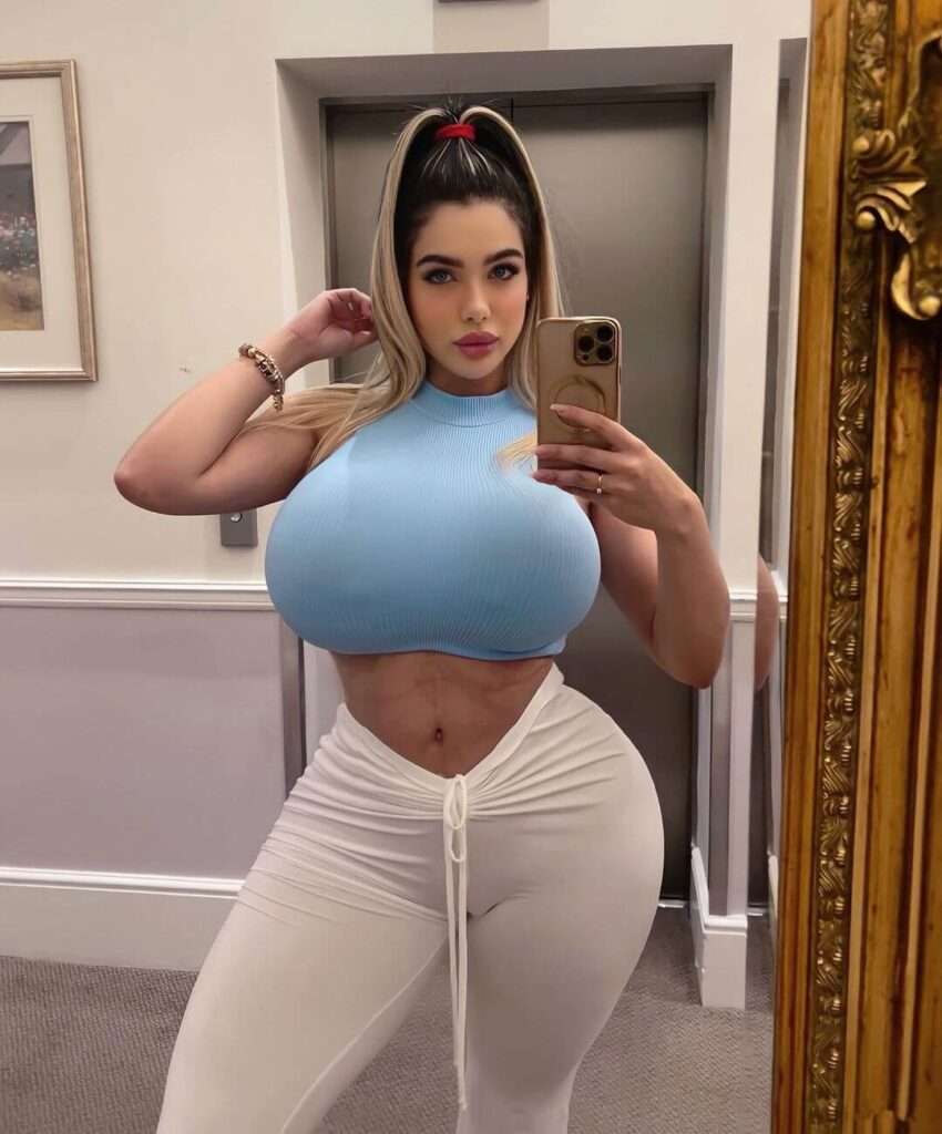 Adriana Alencar is wearing blue bra over white trouser or standing in front of mirror or posing for the picture