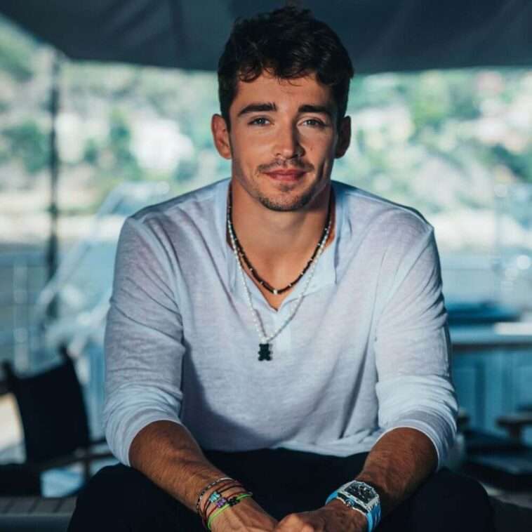Charles Leclerc is wearing white shirt and chain or smiling while posing for the picture